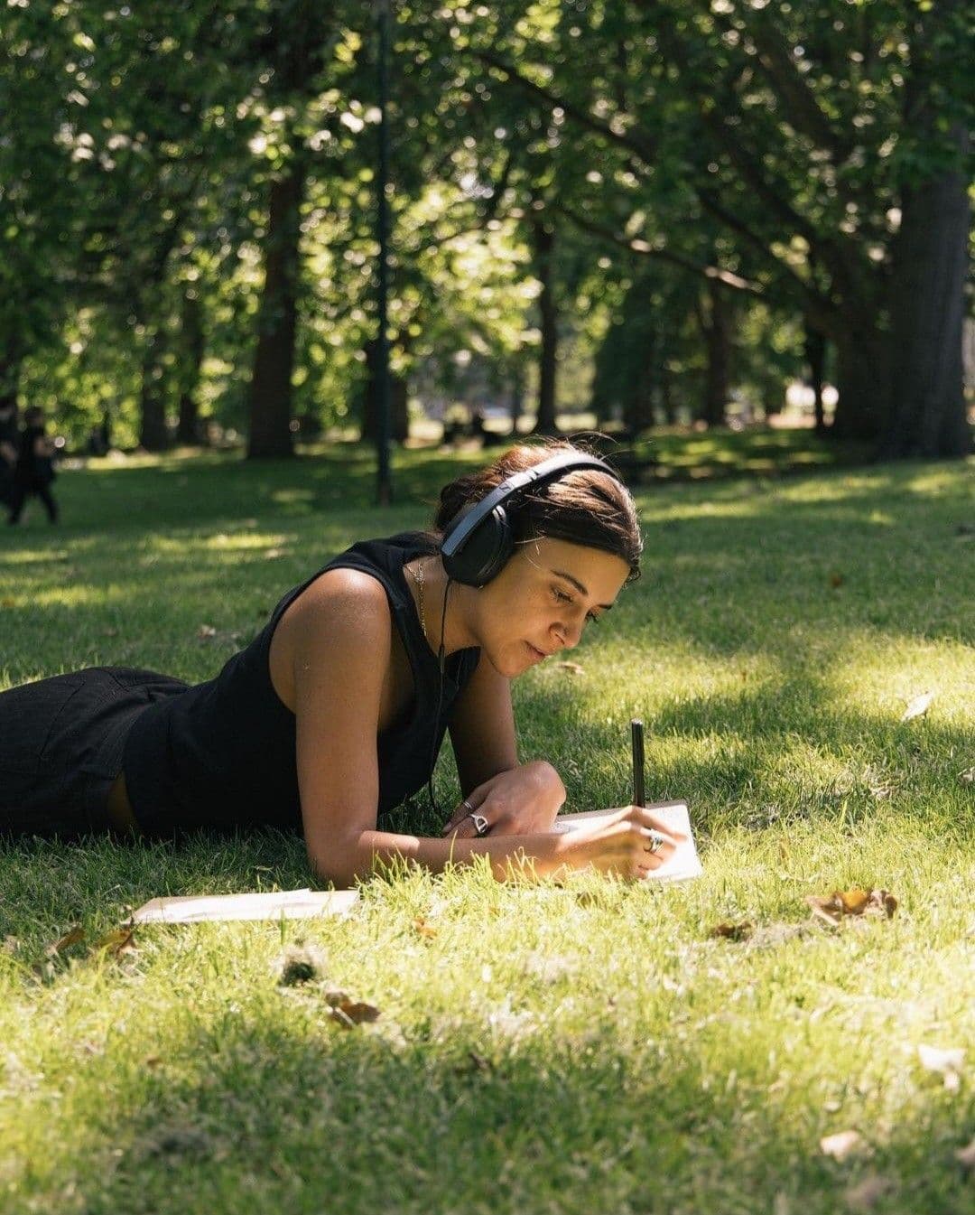 Woman writing in notebook on grass